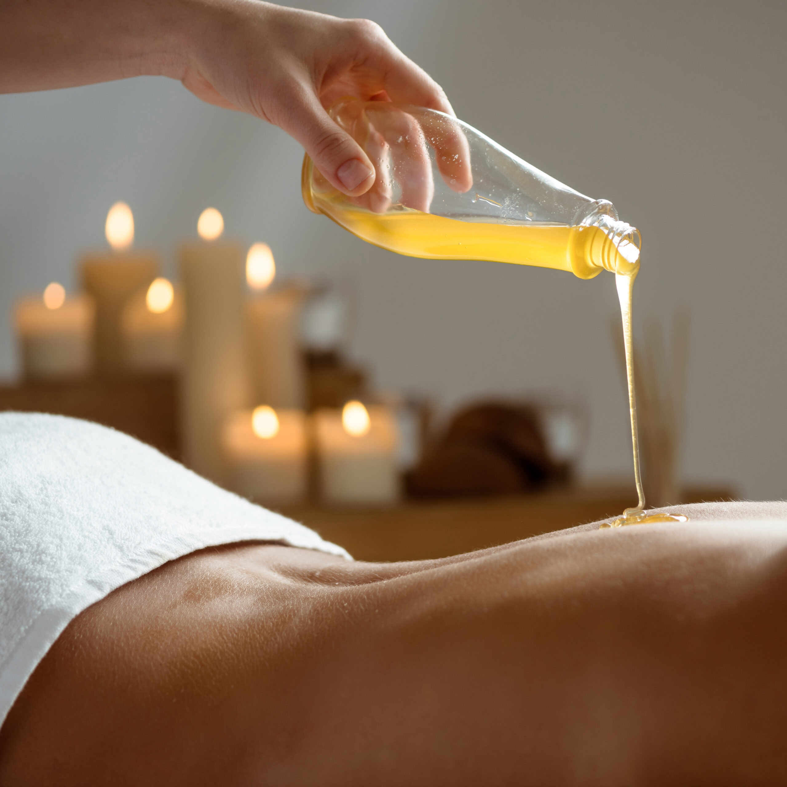 Honey pouring on girl's naked back in spa salon. Copy space.