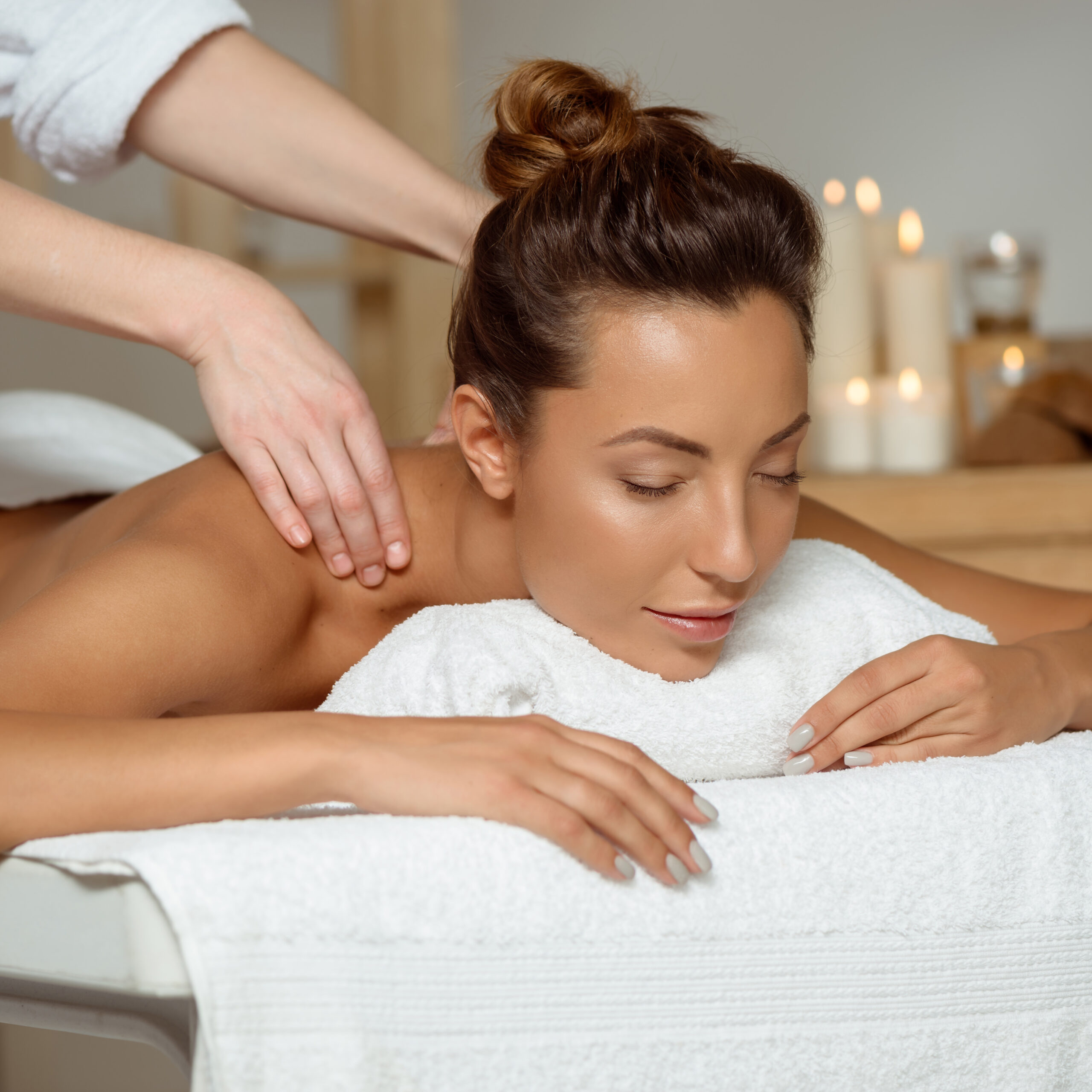 Young attractive brunette girl having massage relaxing in spa salon. Eyes closed. Copy space.